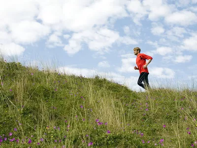 Man running up grassy hillside