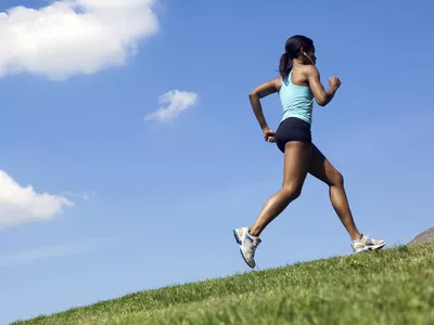 A female runner jogging up a hill outdoors.