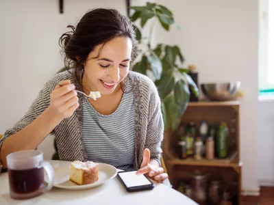 Woman eating looking at phone