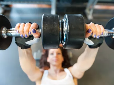 Young woman doing bench press with dumbbells at the gym.