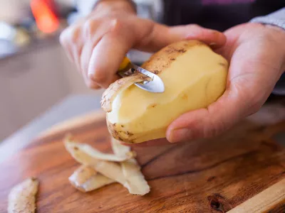 hands holding and peeling a potato
