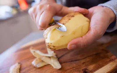 hands holding and peeling a potato