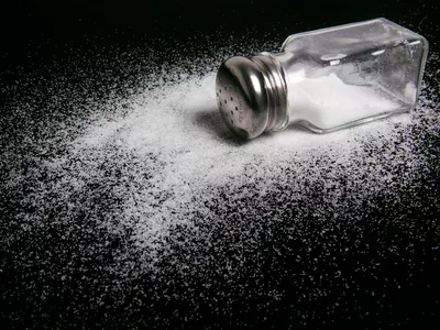 Spilled salt shaker on black countertop