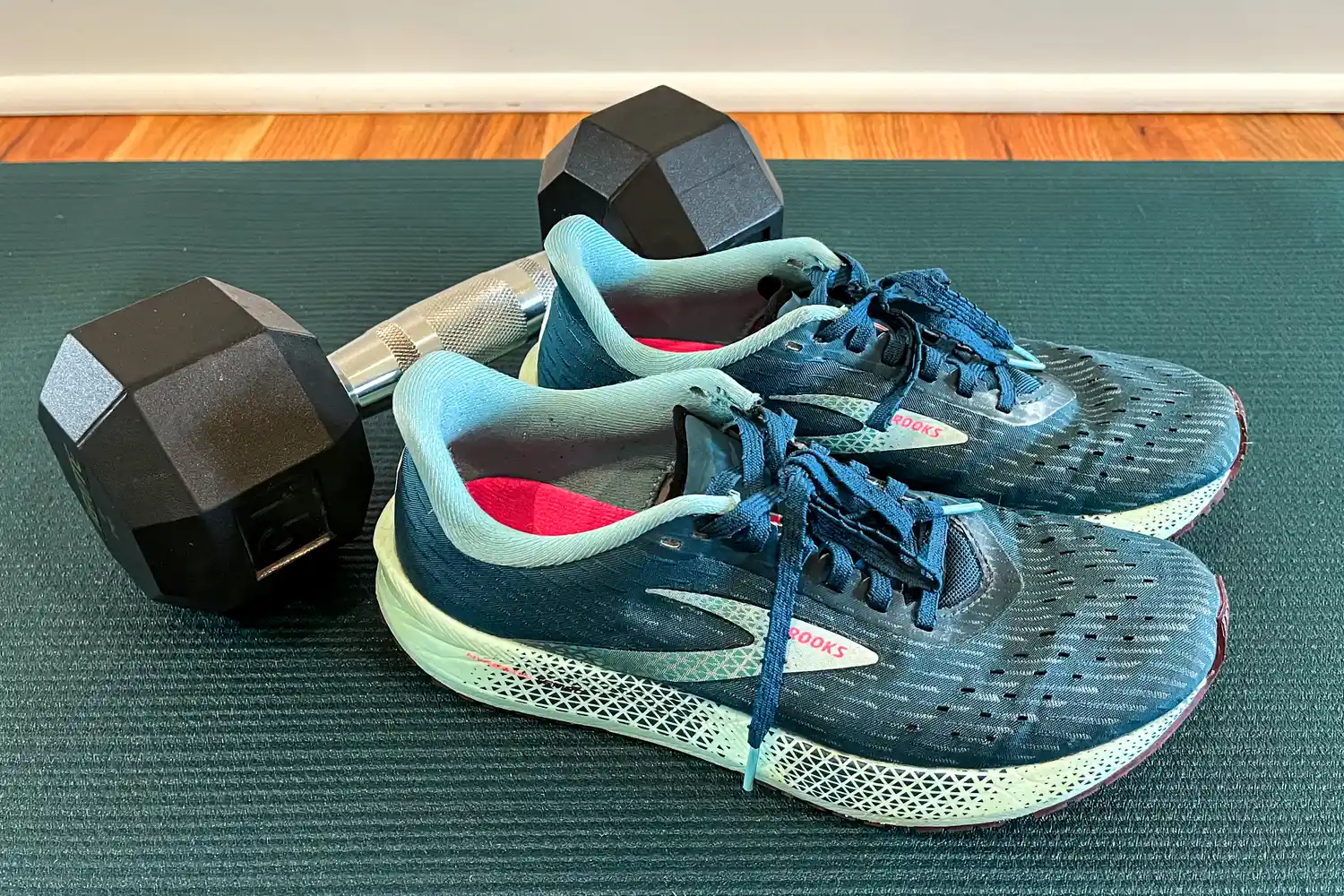 A pair of sneakers placed next to a dumbbell on an exercise mat
