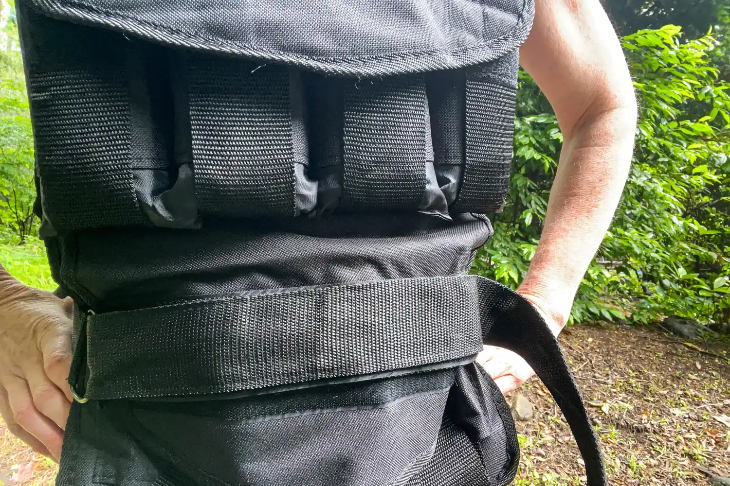 A person wears the CAP Barbell 20-150 Lb Adjustable Weighted Vest with the strap around their waist