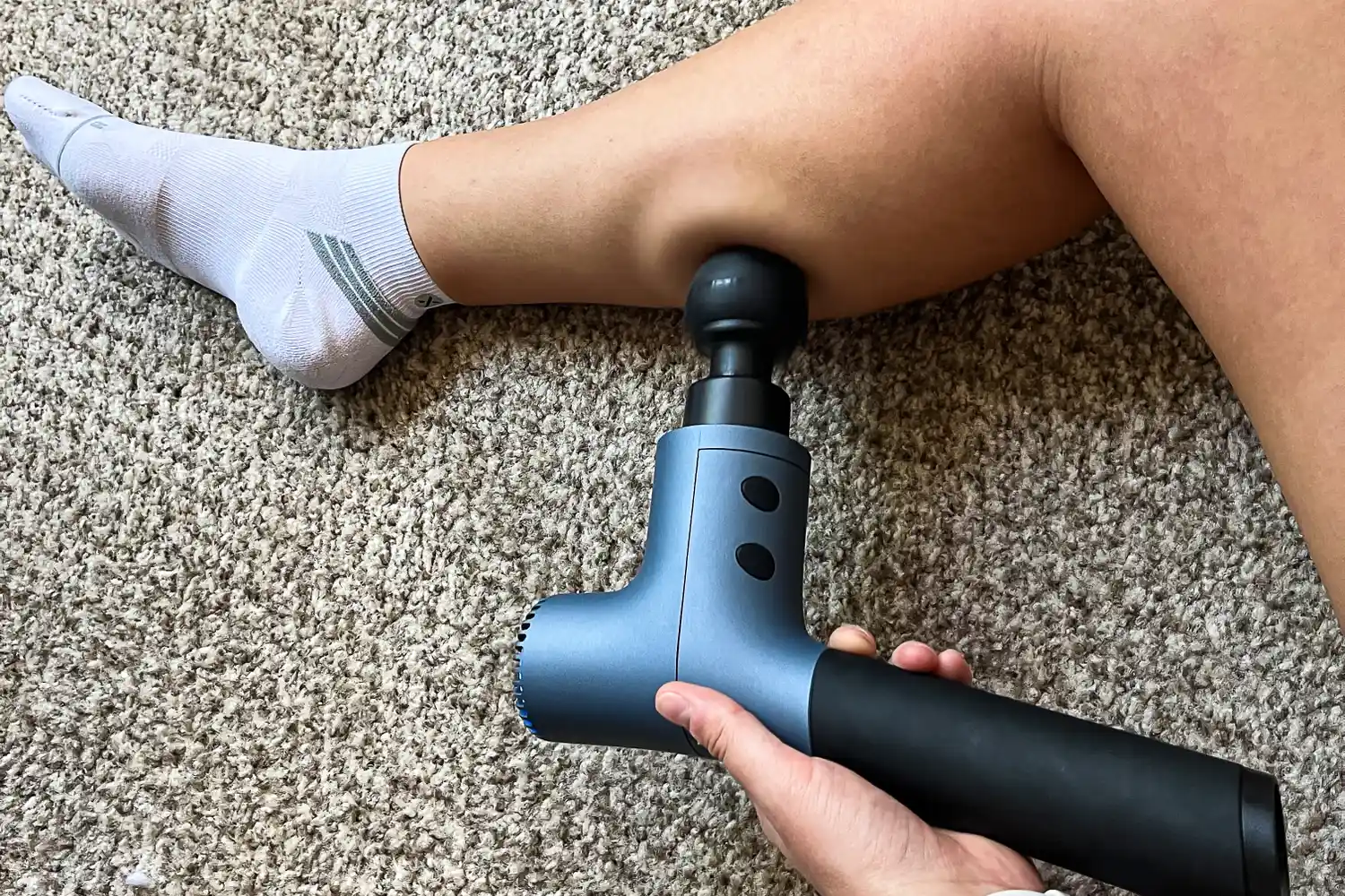 A person uses the Ekrin 365 Massage Gun on their calf