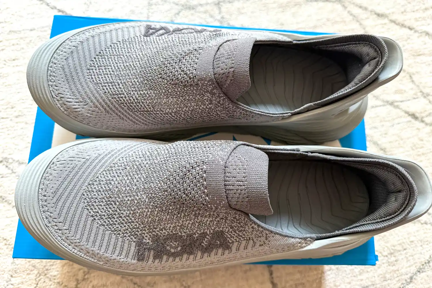 An overhead view of a pair of Hoka Restore TC Recovery Shoes on a shoebox