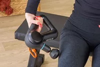 A person using the Theragun Prime on the side of their thigh