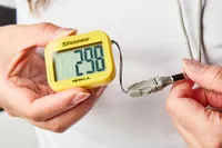 A person holds the strap on the NESKLA 3D Pedometer with Large Digital Display