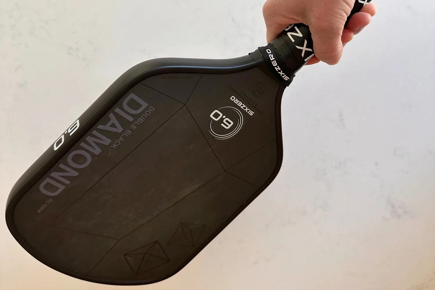 A person grips the Six Zero 16mm Double Black Diamond Control Pickleball Paddle