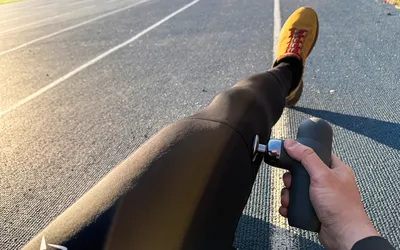 A person uses the Renpho Mini Thermal Massage Gun on their leg