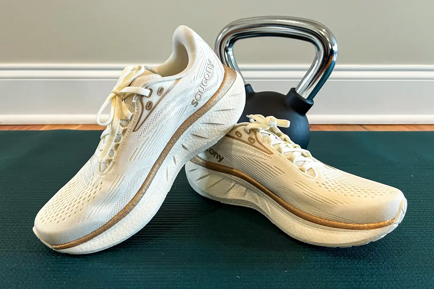 A pair of athletic running shoes on a mat with a kettlebell in the background