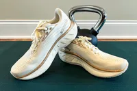 A pair of athletic running shoes on a mat with a kettlebell in the background