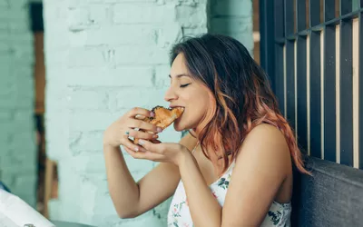 Woman eating croissant in coffee shop